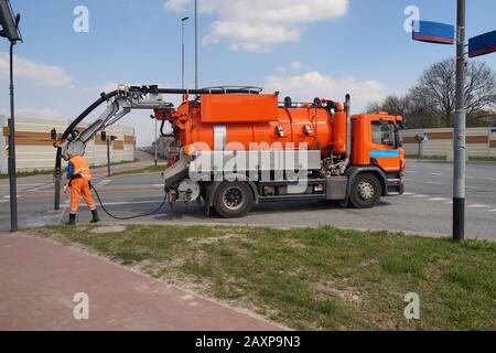 Arbeiter und Spezialwagen. Kanalisationsmanöcher reinigen. Stockfoto