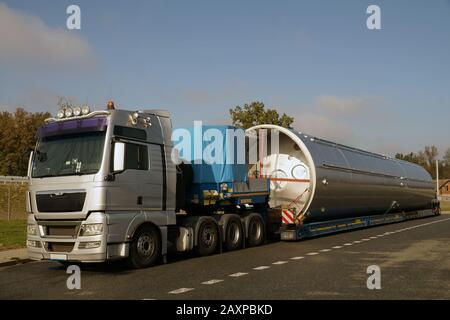 Blick auf einen silberfarbenen LKW, Tieflader-Sattelanhänger und überdimensionale Last. Stockfoto