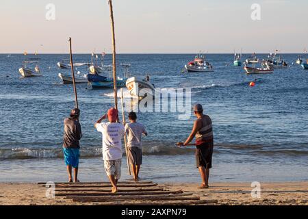 Puerto Escondido, Oaxaca, Mexiko - Fischerboote kommen im Morgengrauen am Hauptstrand von Puerto Escondido an, um gefangenen Fisch zu verkaufen. Der Kapitän lenkt den Bo Stockfoto