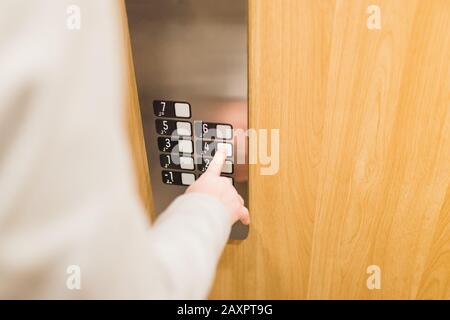 Nahaufnahme des Geschäftsmannes, der in einem modernen Aufzug aus Holz und Stahl drückt. Stockfoto
