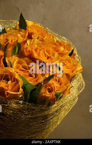 Blumenstrauß mit wunderschönen Teerosen in Vase, mit goldenem Metallic-Dekor, drinnen Stockfoto