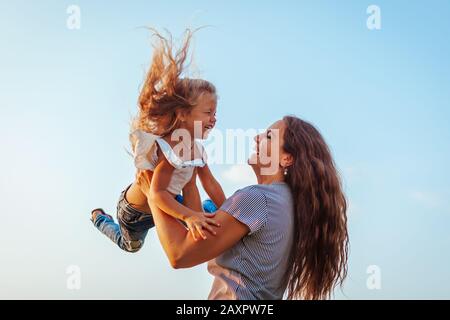 Muttertag. Frau spielt und hat Spaß mit Tochter im Frühlingspark. Mutter wirft Kind ins Freie. Stockfoto