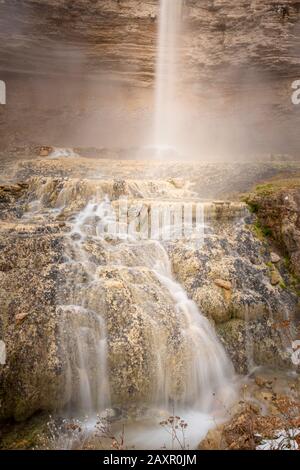 Eine lange Einwirkung eines Wasserfalls, der durch gelben und braunen Stein kaskadiert wird Stockfoto