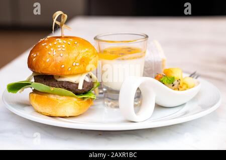 Kleiner Burger und Leidenschaft Obstpudding aus Glas mit gemischten Früchten und Wraps Sandwish auf weißem Gericht für Seminarbrising-Zeit. Stockfoto