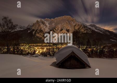 Heuhaufen auf dem sogenannten "Kaffeeplatz" oberhalb von Mittenwald mit Blick auf den westlichen Karwendel und den beleuchteten Ort. Nachtszene. Stockfoto