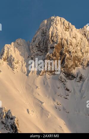 Die obere westliche Karwendelspitze am Mittenwald im letzten warmen Licht der untergehenden Sonne im Winter mit viel Schnee und Schneestrom Stockfoto