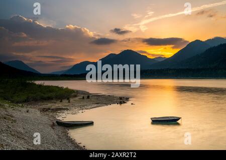 Sonnenuntergang mit Fischerboot am Ufer des Sylvenstein imponierendem Reservoir in Karwendel Stockfoto