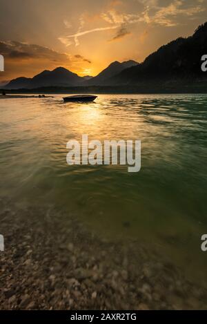 Sonnenuntergang mit Fischerboot am Ufer des Sylvenstein imponierendem Reservoir in Karwendel Stockfoto