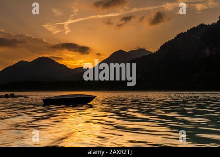 Sonnenuntergang mit Fischerboot am Ufer des Sylvenstein imponierendem Reservoir in Karwendel Stockfoto