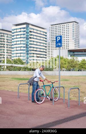 Business, Lifestyle, Verkehr und Menschen Konzept - junge Mann Parkplatz Fahrradverleih am Ort Straße Stockfoto