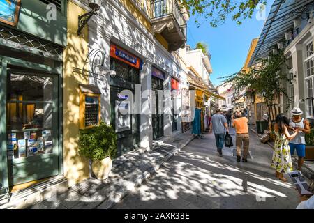 Touristen kaufen in einer der vielen engen Fußgängerstraßen von Geschäften und Cafés im historischen Stadtteil Plaka in Athen, Griechenland. Stockfoto