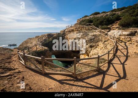 Natürliches Felsloch auf dem Klippenpfad entlang der Felsküste von Praia da Marinha nach Benagil, Algarve, Bezirk Faro, Portugal Stockfoto