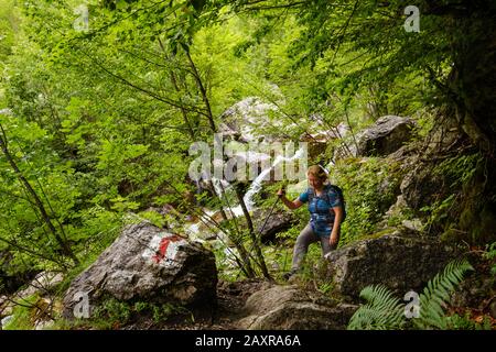 Wandernde Frau am Wasserfall von Grunas, Ujëvara e Grunasit, in der Nähe von Theth, Theth-Nationalpark, albanische Alpen, Prokletije, Qark Shkodra, Albanien Stockfoto