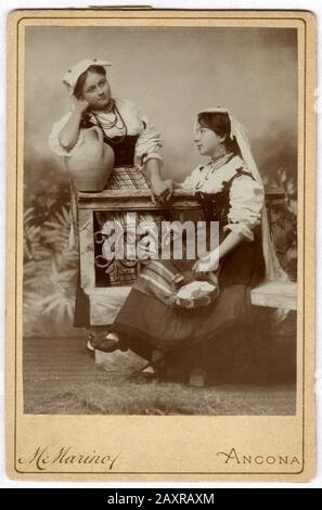 Ca, ANCONA, ITALIEN: Porträt der italienischen Frauen im Folkkostüm der REGION MARKEN . Foto von M. MARINO, Ancona . Der marinesische Fotograf, nachdem er offizieller Fotograf des Herzog von Genua Savoia geworden war, zog von Ancona ( Piazza Plebiscito, 5 ) nach Rom ( Via dei Serpti, 74 ). 1918.- PORTRÄT - RITRATTO - GESCHICHTE - FOTO STORICHE - ITALIEN - OTTOCENTO - 800 - 800 - KOSTÜM FOLKLORISTICO REGIONALE - FOLKLORE - MODA - MODE - donna - Donne - Schuhe - Scarpe bianche - Hut - cappello - anfora - Tamburello - Mano nella mano - Hand in Hand - amiche - Freunde - amicizia - friendshi Stockfoto