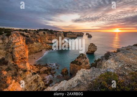 Felsküste bei Praia da Marinha bei Sonnenaufgang, Lagoa, Algarve, Bezirk Faro, Portugal Stockfoto