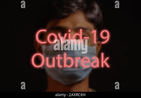 COVID-19 Wuhan Roman Coronavirus oder 2019-nCoV, Mann mit blauer medizinischer Gesichtsmaske auf dem Hintergrund und geschrieben Covid-19 Ausbruch. Konzept des Coronavirus Stockfoto