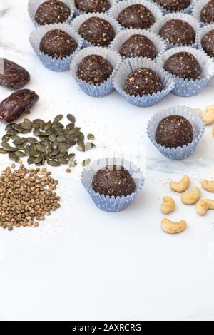 Hausgemachte vegane Kakao datieren Samen und Nuss-Energiekugeln. Hergestellt mit medjool Datteln, Cashew Nüssen, Hanf, Sonnenblumen und Kürbissamen und Kokosnuss Stockfoto