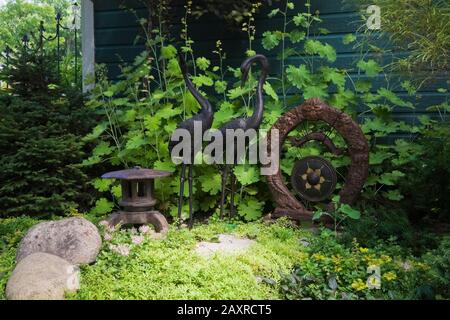 Japanische Pagode, schwarze Reihervogel- und Gong-Skulpturen im Hinterhof Zen-Garten im Sommer. Stockfoto