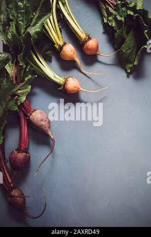 Mischung aus roten und goldenen Rüben auf grauem Hintergrund. Lebensmittelhintergrund. Konzept des gesunden Essens. Getontes Bild. Vertikal Stockfoto
