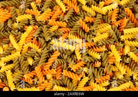 Uncooked tricolore Fusilli Pasta verdreht den Hintergrund Stockfoto