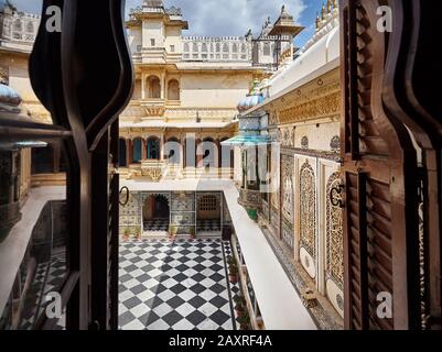 Stadtpalastmuseum mit Schachbrettboden und schöner Architektur in Udaipur, Rajasthan, Indien. Blick vom Balkonfenster. Stockfoto