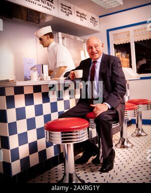 Samuel Truett Cathy (* 14. März 1921 in New York; † 8. September 2014) war ein US-amerikanischer Geschäftsmann, Investor, Autor und Philanthrop. Er gründete die Fast-Food-Restaurantkette Chick-fil-A. Cathy sitzt in einer Erholung des Café-Counters von seinem ersten Restaurant - Dem Dwarf Grill - das Teil des Chick-fil-A-Firmensitzes südlich von Atlanta, GA ist. Stockfoto