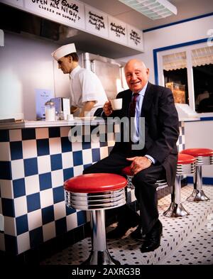 Samuel Truett Cathy (* 14. März 1921 in New York; † 8. September 2014) war ein US-amerikanischer Geschäftsmann, Investor, Autor und Philanthrop. Er gründete die Fast-Food-Restaurantkette Chick-fil-A. Cathy sitzt in einer Erholung des Café-Counters von seinem ersten Restaurant - Dem Dwarf Grill - das Teil des Chick-fil-A-Firmensitzes südlich von Atlanta, GA ist. Stockfoto