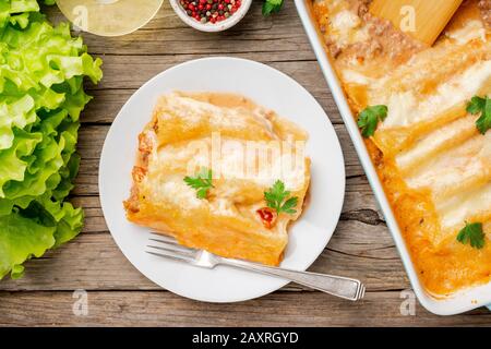 Cannelloni mit Füllung aus gemahlenem Rindfleisch, Tomaten, gebacken mit Bechamel-Tomatensauce, Draufsicht, altem dunklem Holzhintergrund Stockfoto