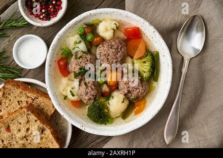 Fleischbällchen Suppe in weißem Teller auf altem rustikalem Holztisch, Draufsicht Stockfoto