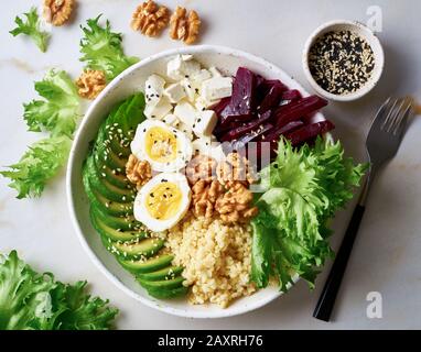 Buddha-Schüssel, ausgewogene Speisen, vegetarische Speisekarte. Grauer Marmortisch, Draufsicht. Eier, Avocado, Salatsalat, Bulgur, Rote Bete, Tofu Stockfoto