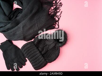 Flat Lay Winter oder Herbst warm Woman Accessoires - schwarzer Strickschal, Hut auf hellrosa Hintergrund, Kopierraum Stockfoto