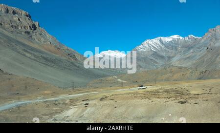 Ein Touristenauto, der weit entfernt von der langen Bergtour ist. Zu weit entfernten Gipfeln führt Schnee bedeckter Wüstenhimalaya. Mount Everest Basislager. Mys Stockfoto