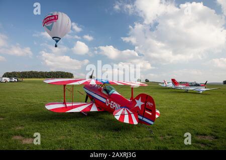 Pitts S1-E Doppelflugzeug auf einer Wiese, Heißluftballon in der Luft, Luftschau, Flugplatzfest Degerfeld, Schwäbische Alb, Deutschland Stockfoto