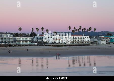 Ein kalifornisches Hotel nach Sonnenuntergang am Strand mit Palmen, die im Meer reflektiert werden. Stockfoto