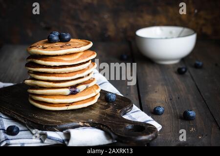 Ricotta pfannert mit Blaubeeren auf dunklem Holzhintergrund. Rustikaler Stil. Bequemes Essen. Stockfoto