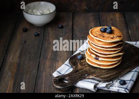 Ricotta pfannert mit Blaubeeren auf dunklem Holzhintergrund. Rustikaler Stil. Bequemes Essen. Stockfoto