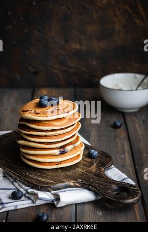 Ricotta pfannert mit Blaubeeren auf dunklem Holzhintergrund. Rustikaler Stil. Bequemes Essen. Stockfoto