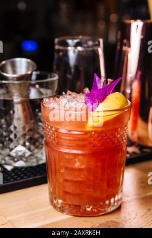 Frisch gepresste Grapefruit und Orangensaft in einem Glas, oben dekoriert mit einer Zitronenscheibe, frischen Blumen und Eisstücken. Stockfoto