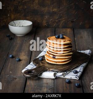 Ricotta pfannert mit Blaubeeren auf dunklem Holzhintergrund. Rustikaler Stil. Bequemes Essen. Stockfoto