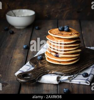 Ricotta pfannert mit Blaubeeren auf dunklem Holzhintergrund. Rustikaler Stil. Bequemes Essen. Stockfoto