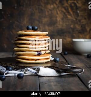 Ricotta pfannert mit Blaubeeren auf dunklem Holzhintergrund. Rustikaler Stil. Bequemes Essen. Stockfoto