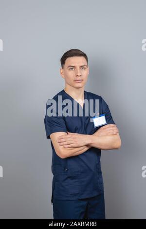 Mann in einer dunkelblauen Uniform, die mit gekreuzten Armen steht Stockfoto