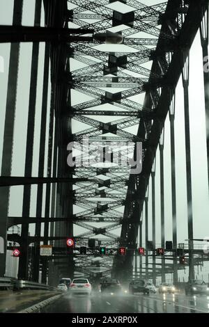 Fahren Sie in südlicher Richtung unter den Metallarbeiten, Querbalken und dem großen Bogen der Sydney Harbour Bridge während der Hauptverkehrszeit im Regen Stockfoto