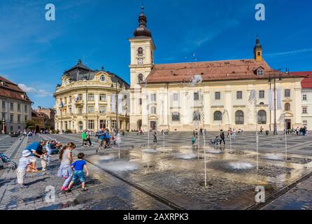 Kinder am Brunnen vor der Römisch-katholischen Kathedrale, Banca Agricola am Piata Stute (großer Platz) in Sibiu, Siebenbürgen, Rumänien Stockfoto