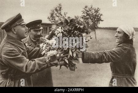 Rote Armee in den 1930er Jahren. Aus dem sowjetischen Propagandabuch von 1937. Eine normale Sowjetin schenkt den Marschällen Voroschilow und Marschall Budyon einen Blumenstrauß Stockfoto