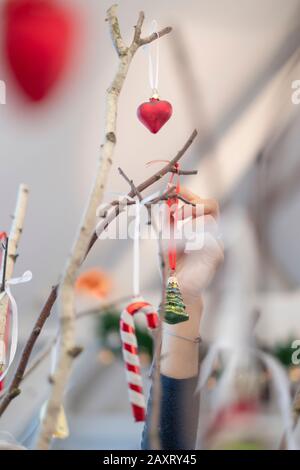 Eine Frau schmückt Birkenzweige mit Weihnachtsdekoration, Herzgläserkugel Stockfoto