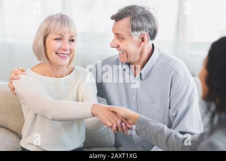 Glückliches älteres Paar, das weiblichen Arzt Handschlag gibt Stockfoto