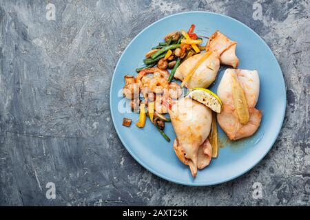 Frische gefüllte Tintenfische mit Champignons gebacken. Gebackene Meeresfrüchte mit Gemüse Stockfoto
