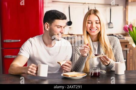 Ein junges romantisches Paar frühstückt in der modernen, hellen Küche Stockfoto
