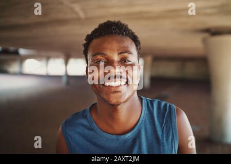Porträt eines fröhlichen afroamerikanischen, sportlichen jungen Mannes, der draußen in die Kamera blickt Stockfoto